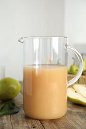 Photo of Fresh pear juice in glass jug on wooden table, closeup