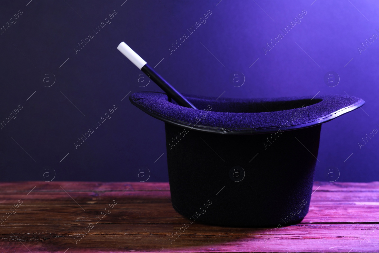 Photo of Black top hat and wand on wooden table, space for text. Magician equipment