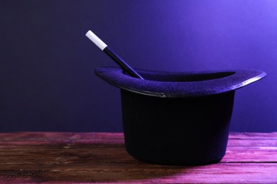 Photo of Black top hat and wand on wooden table, space for text. Magician equipment