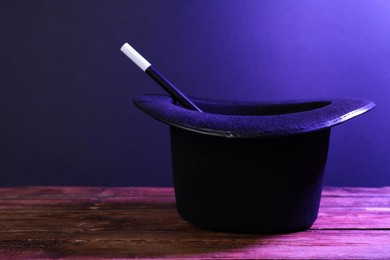 Black top hat and wand on wooden table, space for text. Magician equipment