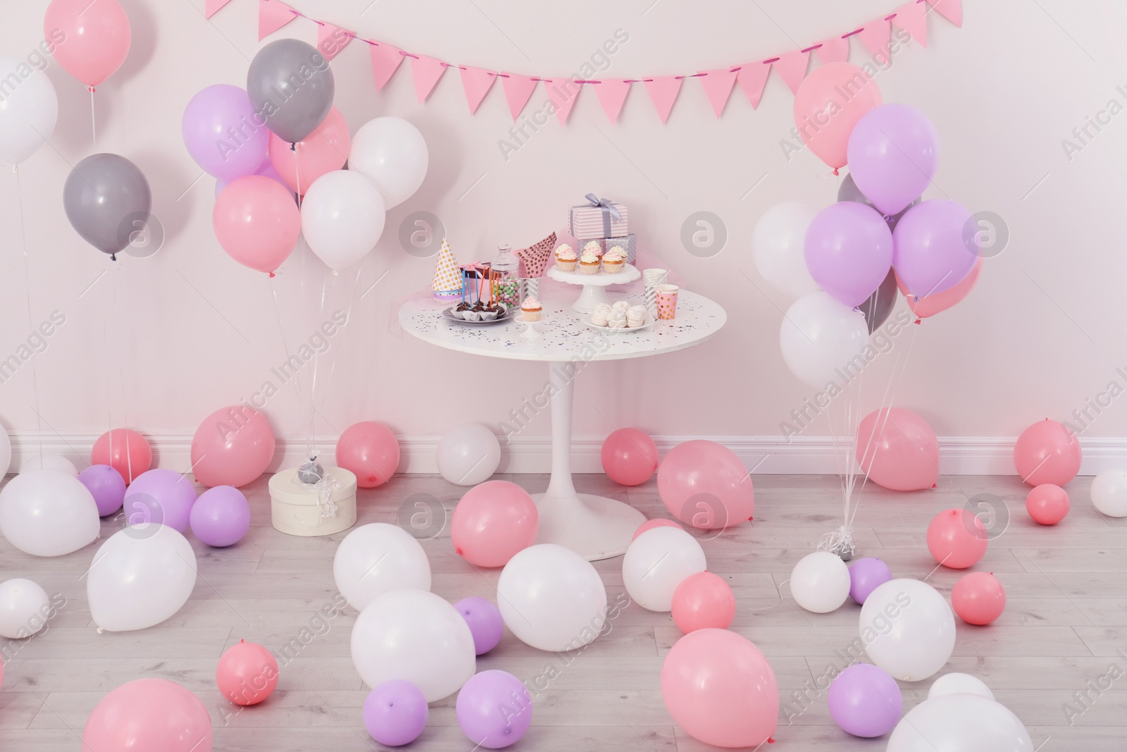 Photo of Party treats and items on table in room decorated with balloons