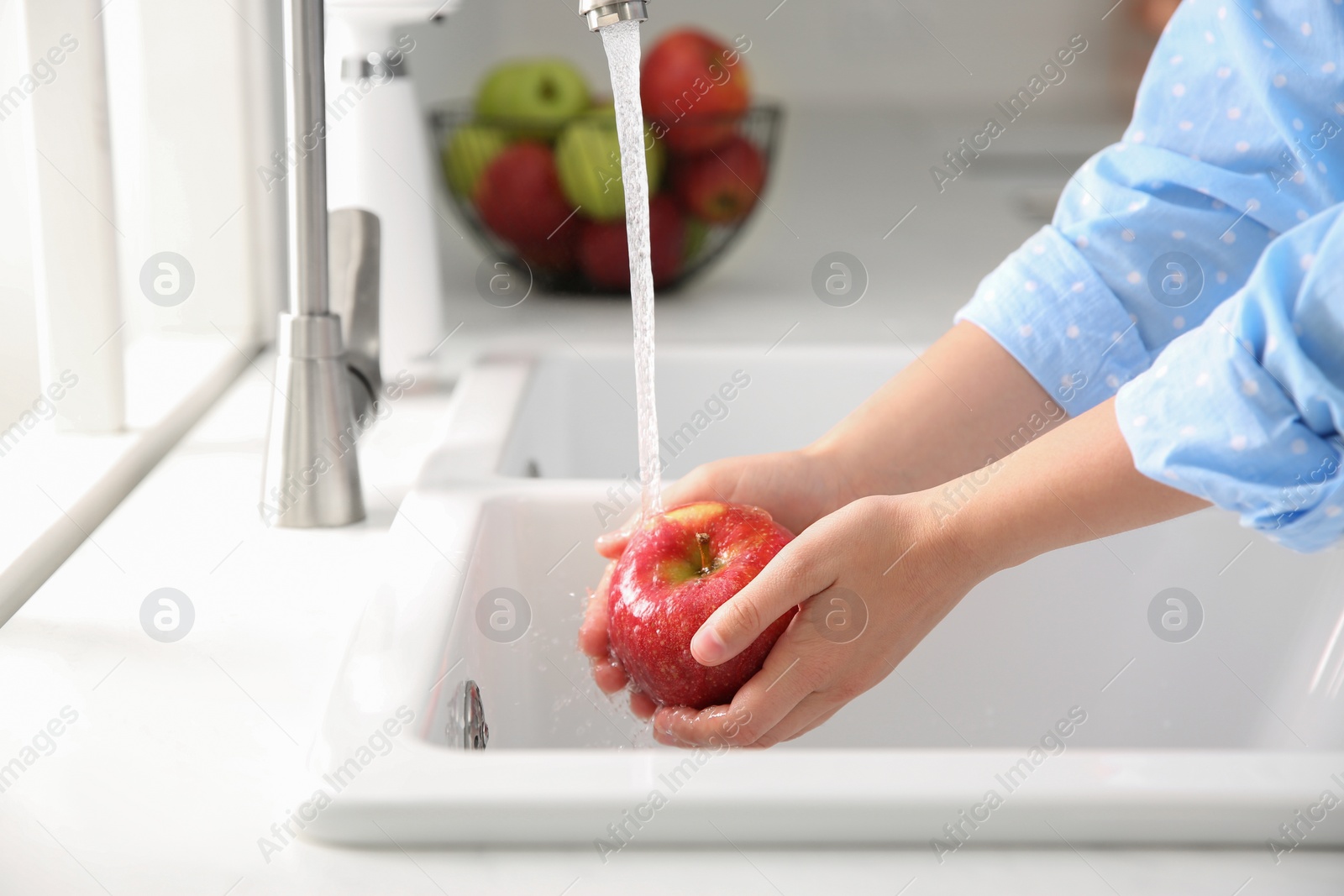 Photo of Woman washing fresh red apple in kitchen sink, closeup