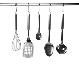 Photo of Set of kitchen utensils hanging against white background