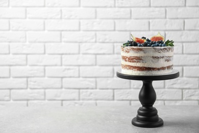 Photo of Delicious homemade cake with fresh berries on table against brick wall. Space for text