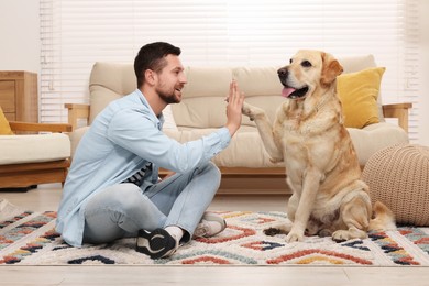 Photo of Man with adorable Labrador Retriever dog at home. Lovely pet