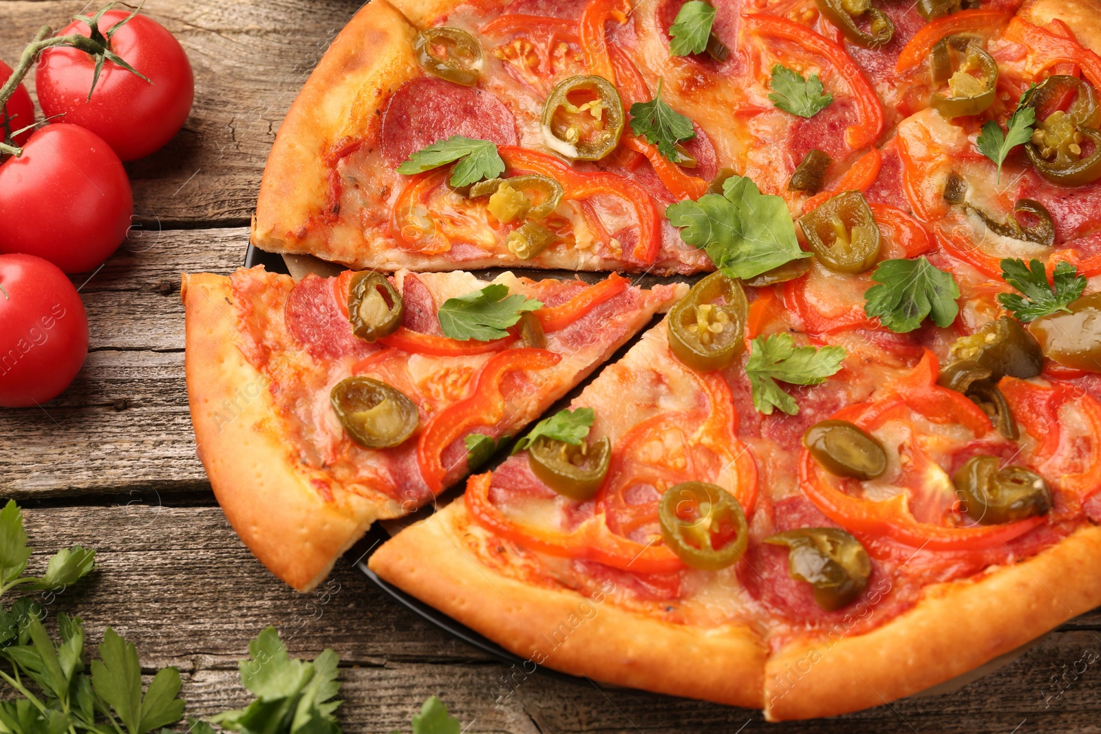 Photo of Delicious pizza Diablo, tomatoes and parsley on wooden table, closeup