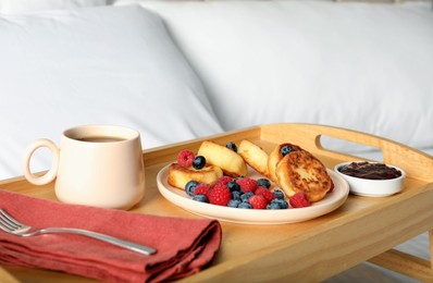 Tasty breakfast served in bedroom. Cottage cheese pancakes with fresh berries and coffee on wooden tray