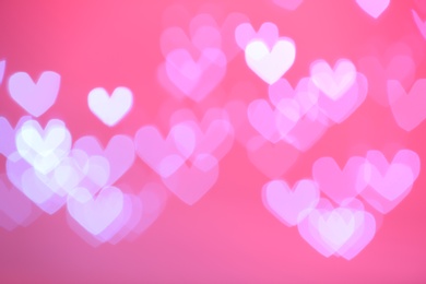 Photo of Blurred view of beautiful heart shaped lights on color background