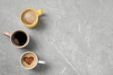 Cups with different aromatic coffee on light grey marble table, flat lay. Space for text