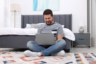 Photo of Happy man having video chat via laptop in bedroom