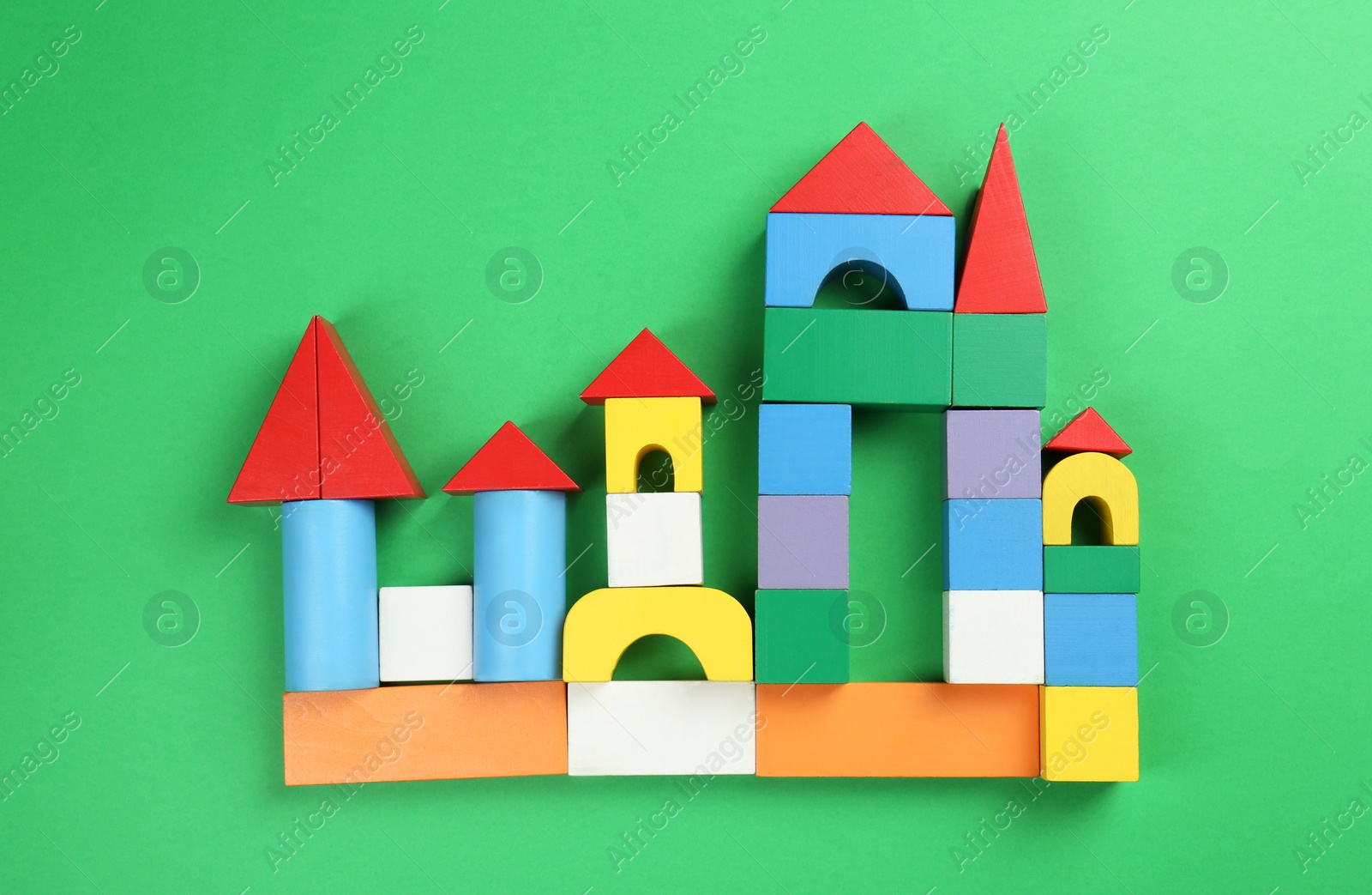 Photo of Beautiful castle of colorful blocks on green background, flat lay. Children's toy