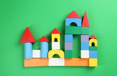 Beautiful castle of colorful blocks on green background, flat lay. Children's toy