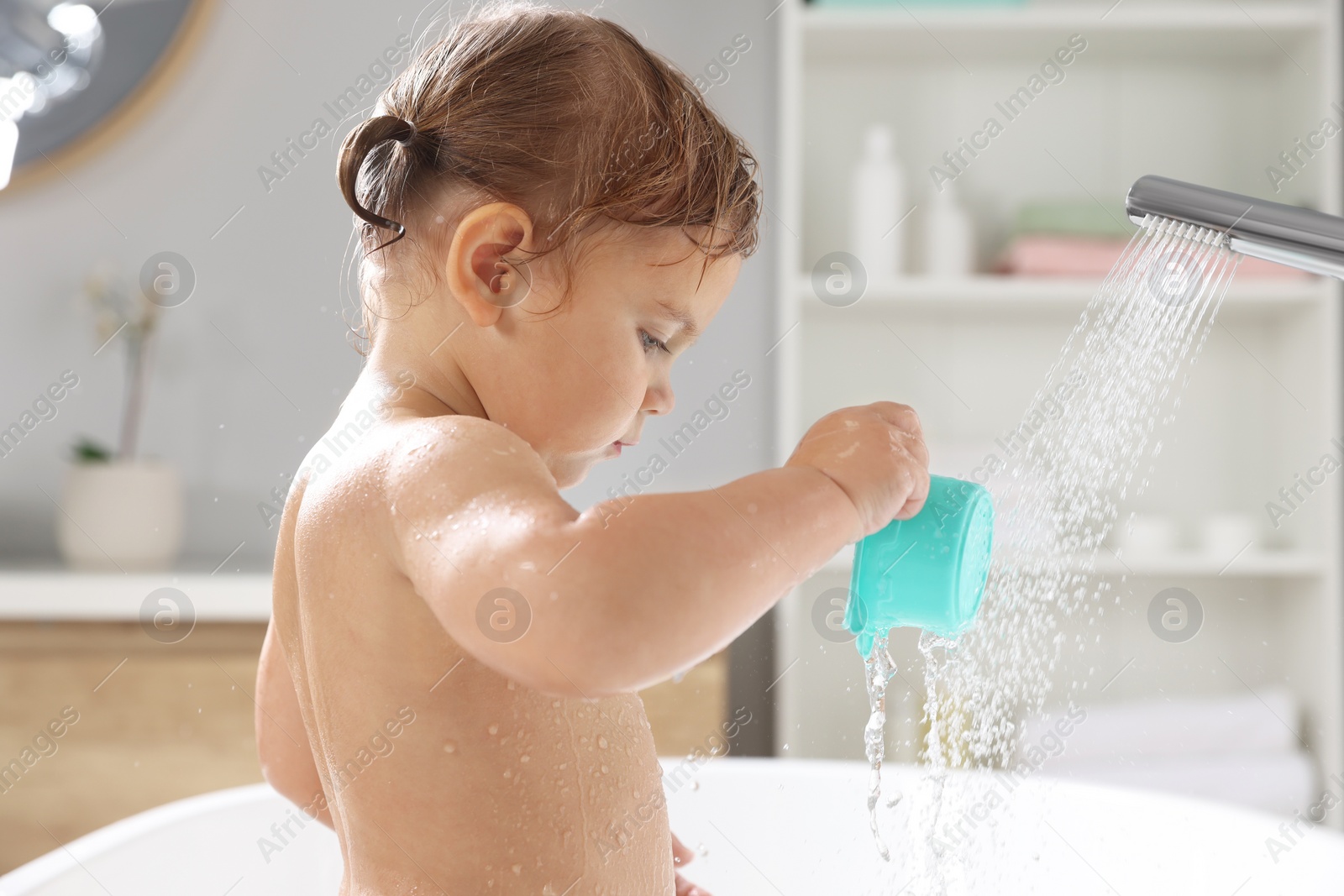 Photo of Cute little girl playing in bathroom at home