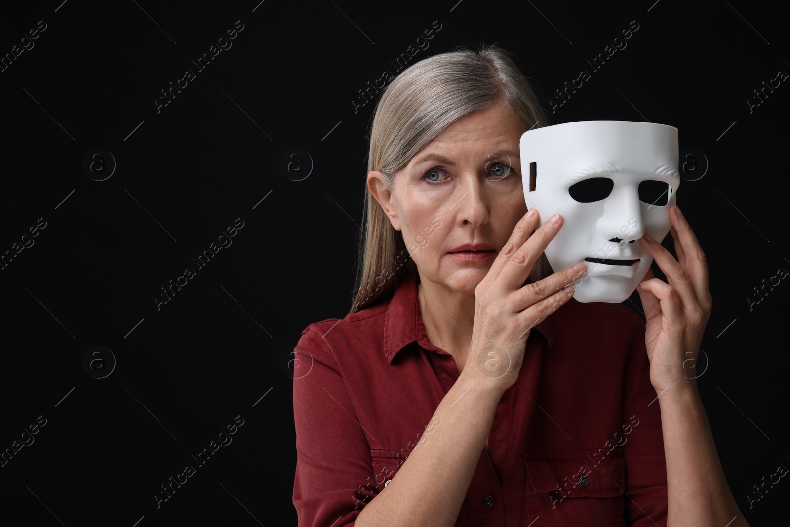 Photo of Multiple personality concept. Woman with mask on black background, space for text