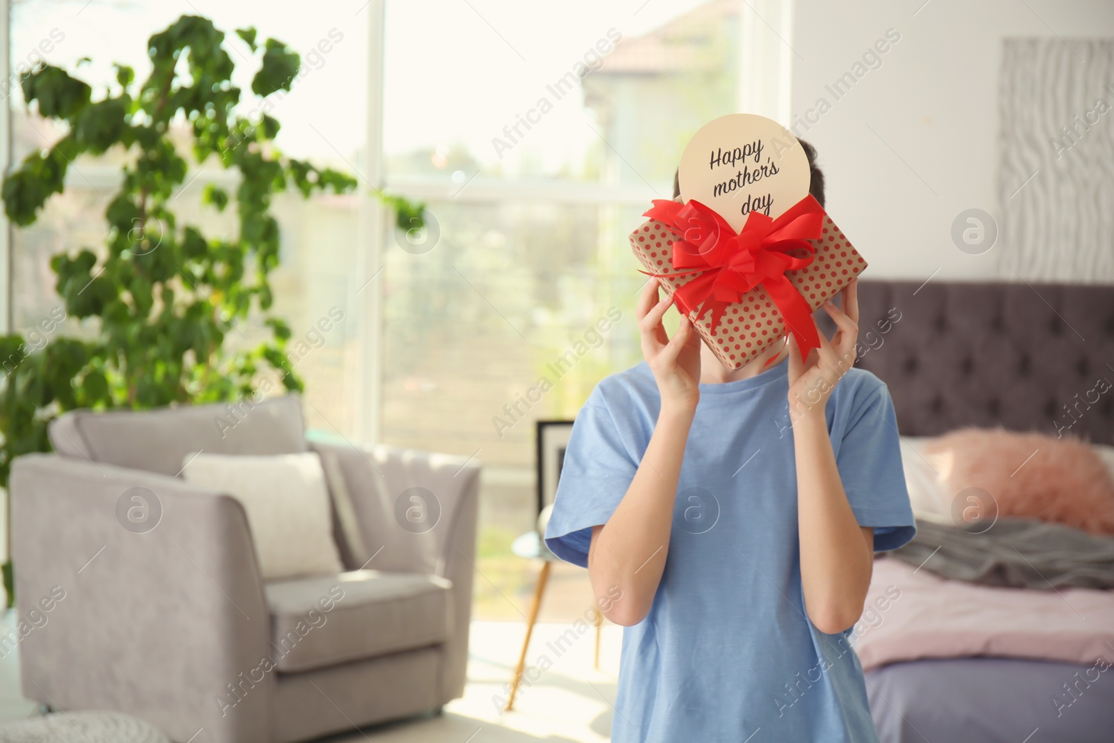 Photo of Little child with gift box for Mother's Day at home