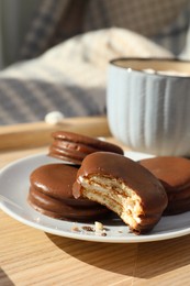Photo of Tasty choco pies and cup of hot drink on wooden tray