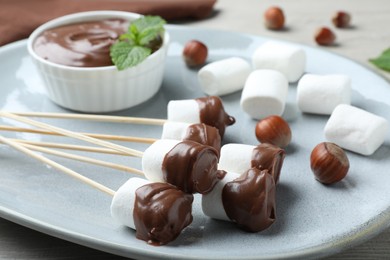 Photo of Tasty chocolate dipped marshmallows on plate, closeup