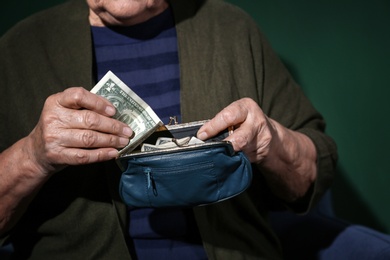 Poor senior woman with money on color background, closeup