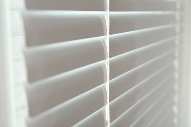 Photo of Closed modern white window blinds, closeup view