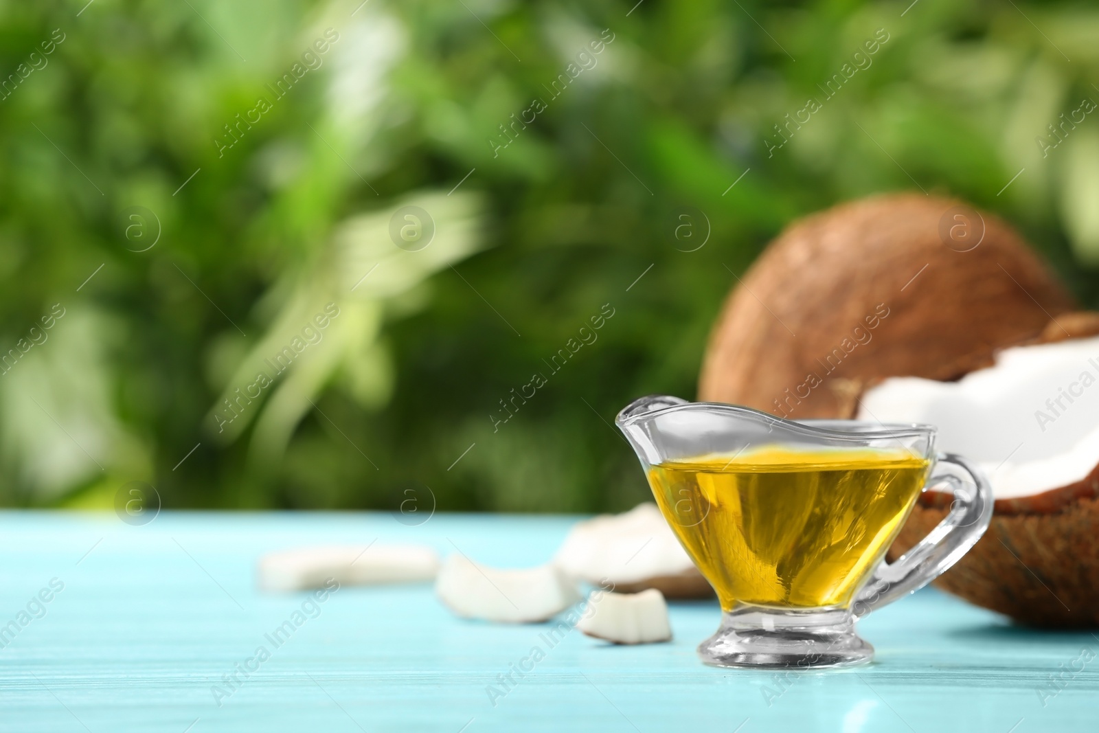 Photo of Gravy boat with coconut oil on table against blurred background. Healthy cooking