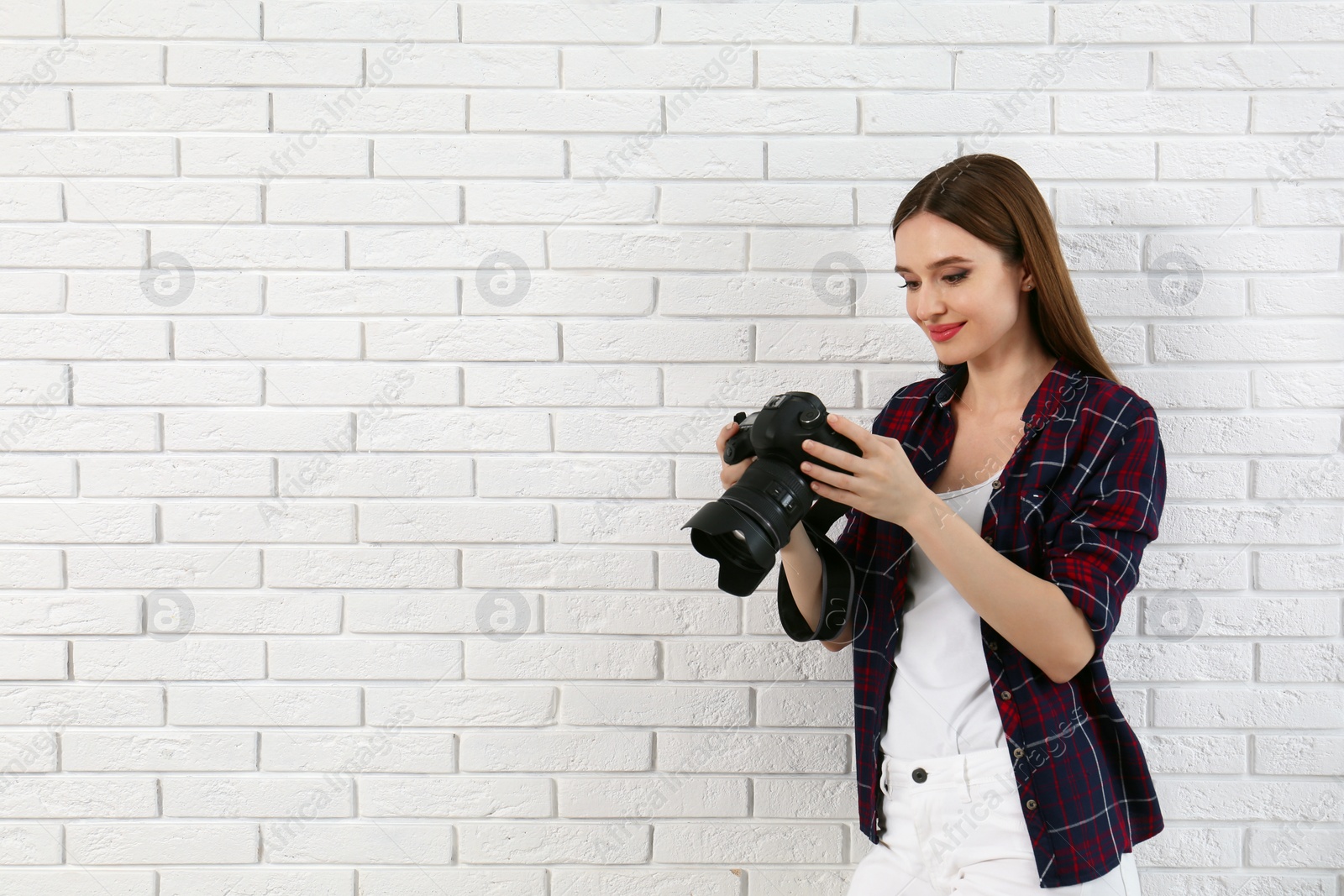 Photo of Professional photographer with modern camera near white brick wall. Space for text