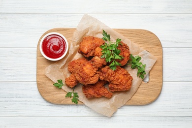 Photo of Tasty deep fried chicken pieces served on white wooden table, top view