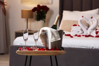 Honeymoon. Sparkling wine and glasses on wooden table in room