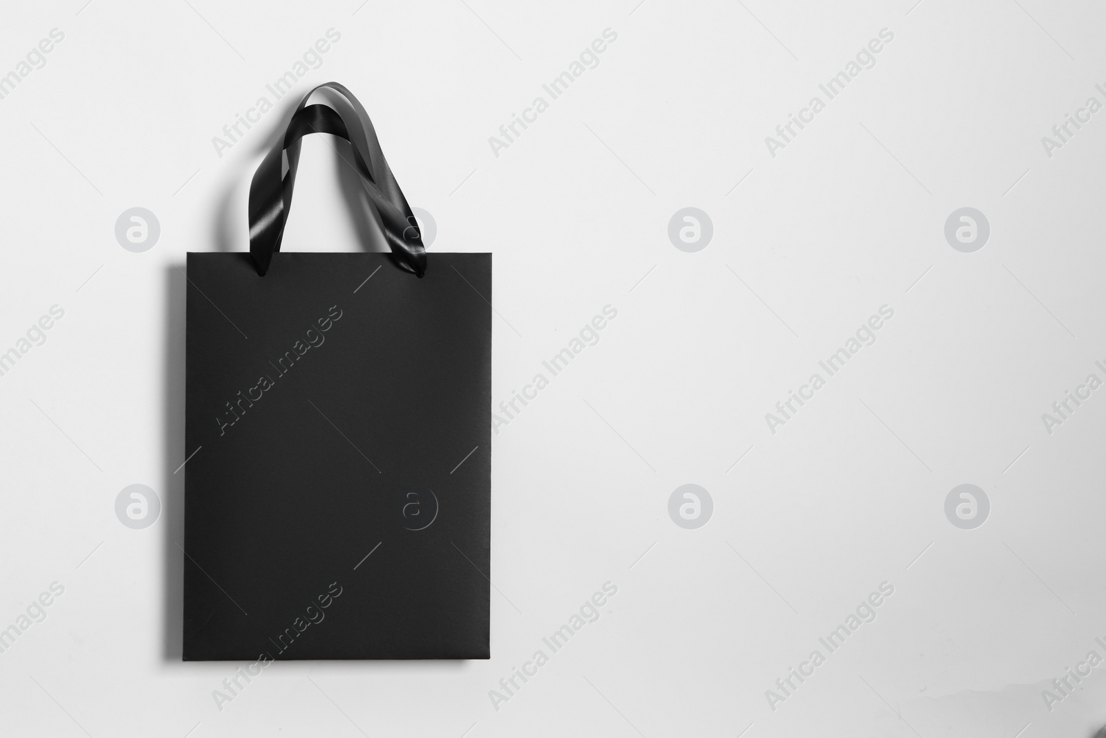 Photo of One black paper shopping bag on white background, top view. Space for text