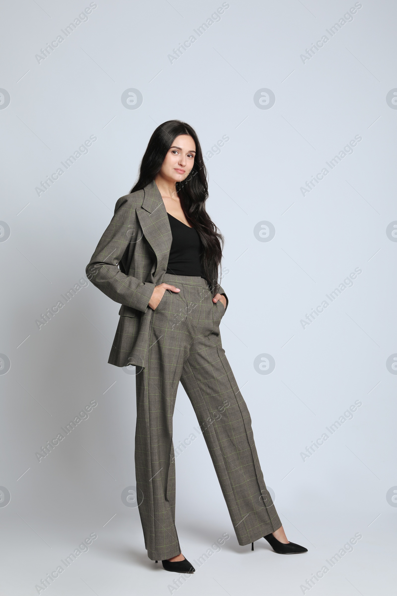 Photo of Full length portrait of beautiful woman in formal suit on light background. Business attire