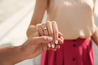 Photo of Lovely couple with beautiful ring after engagement outdoors, closeup