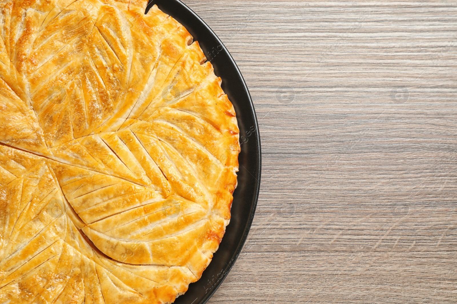 Photo of Traditional galette des rois on wooden table, top view. Space for text