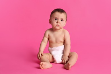 Photo of Cute baby in dry soft diaper sitting on pink background