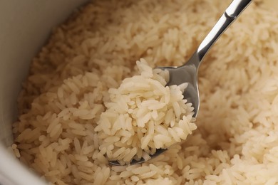 Photo of Pot with delicious rice and spoon, closeup