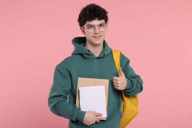 Portrait of student with backpack and notebooks on pink background