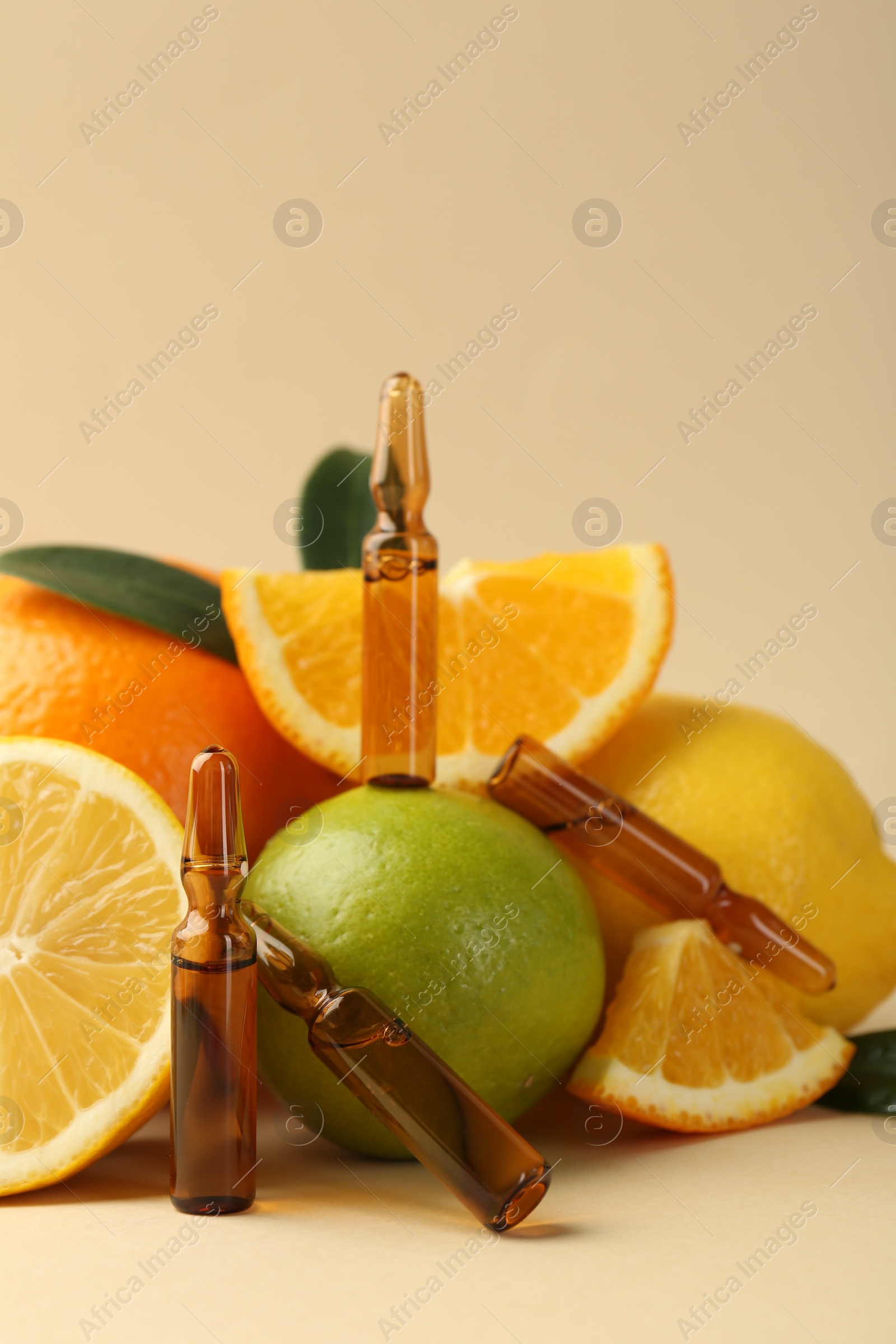 Photo of Skincare ampoules with vitamin C, different citrus fruits and leaves on beige background