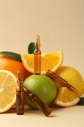 Photo of Skincare ampoules with vitamin C, different citrus fruits and leaves on beige background