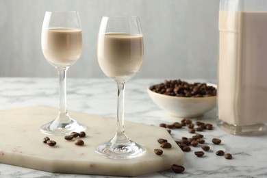 Coffee cream liqueur in glasses and beans on white marble table