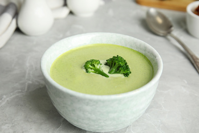 Photo of Delicious broccoli cream soup served on grey marble table