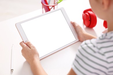 Photo of E-learning. Girl using tablet for studying online at table indoors, closeup