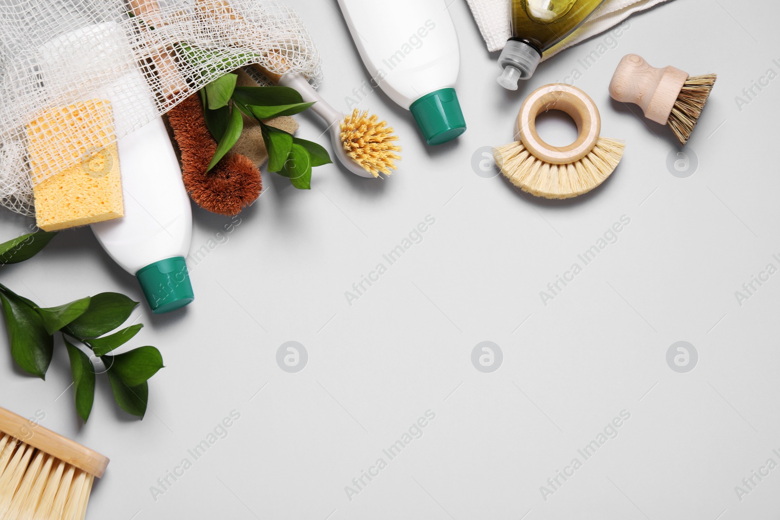 Photo of Flat lay composition with different cleaning supplies on light gray background, space for text