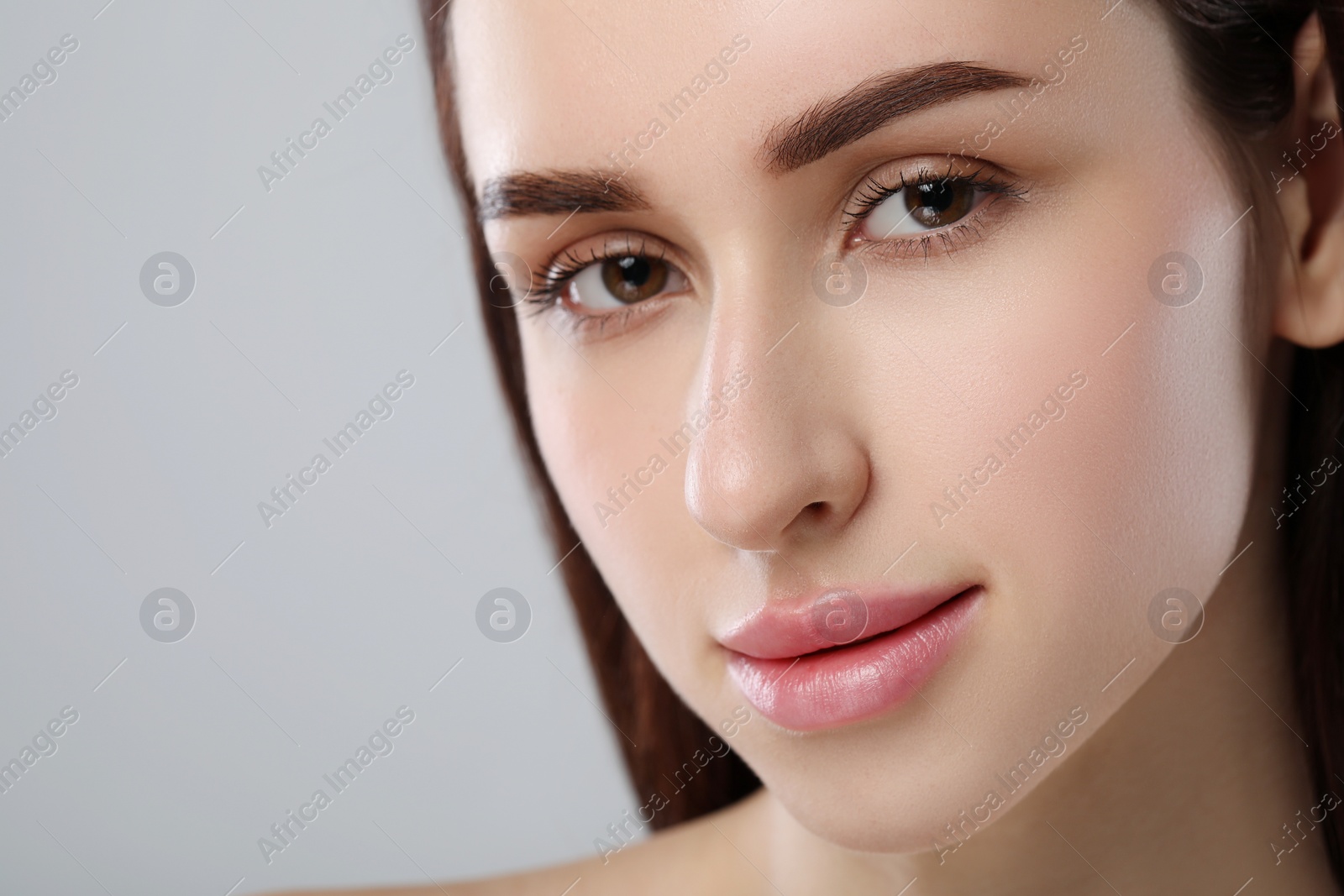 Photo of Beautiful young woman with healthy skin on light grey background, closeup. Space for text