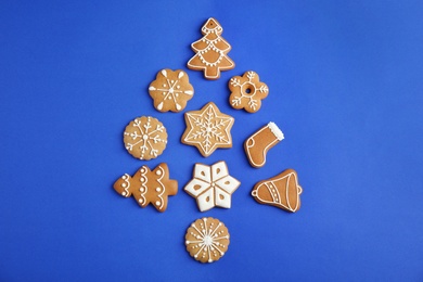 Photo of Christmas tree shape made of tasty homemade cookies on color background, top view