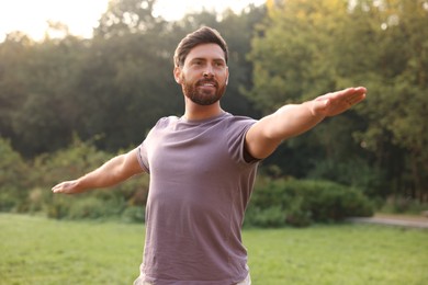Photo of Attractive man practicing yoga in park on sunny day