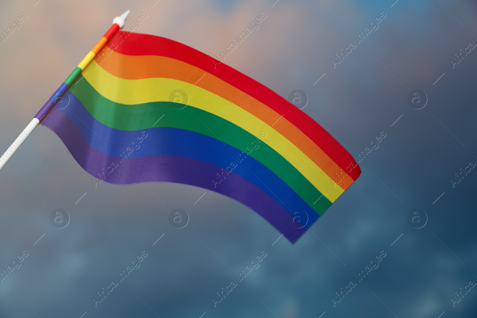 Photo of Bright rainbow LGBT flag against cloudy sky