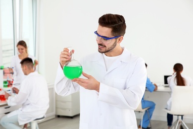 Photo of Medical student with glass flask working in modern scientific laboratory