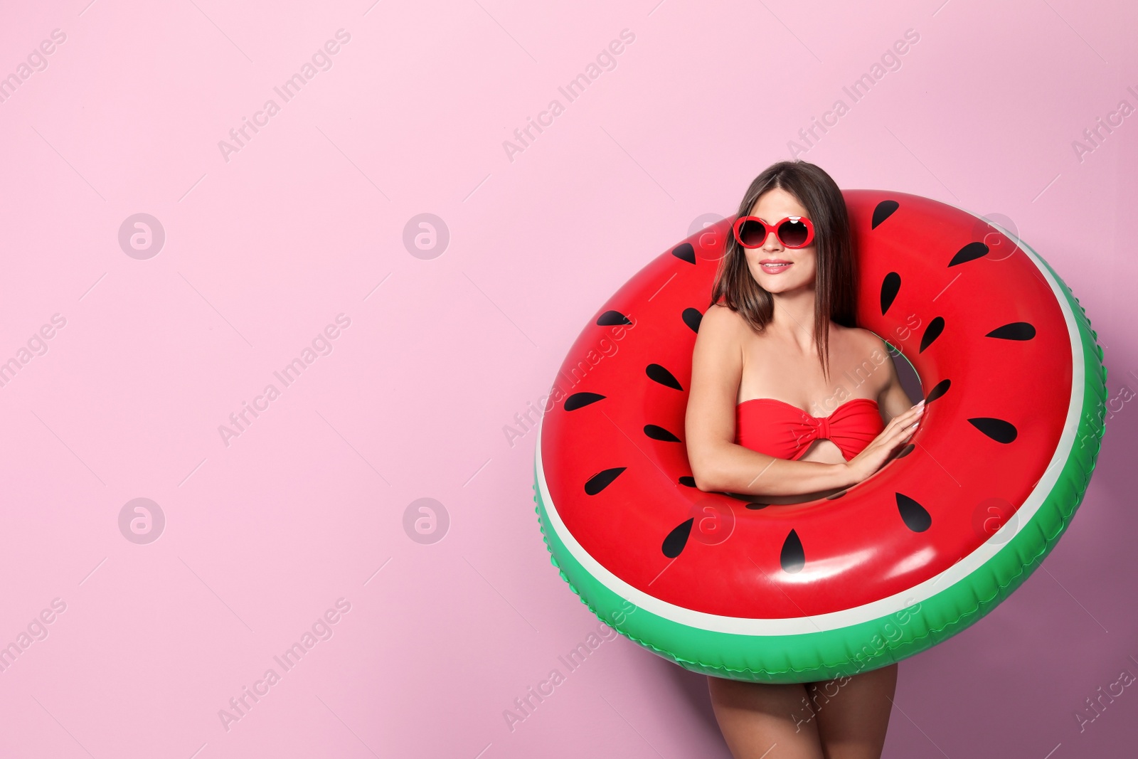 Photo of Sexy young woman in bikini with inflatable ring on color background