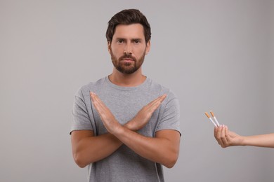 Photo of Stop smoking concept. Man refusing cigarettes on grey background