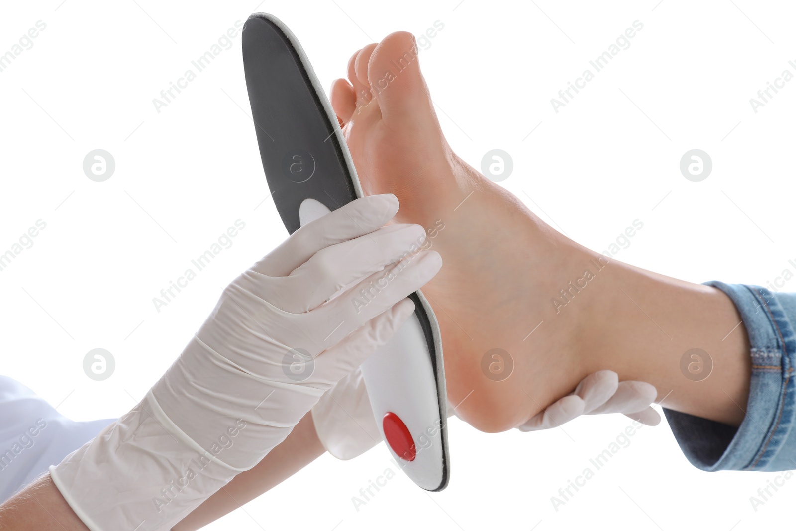 Photo of Orthopedist fitting insole on patient's foot against white background, closeup