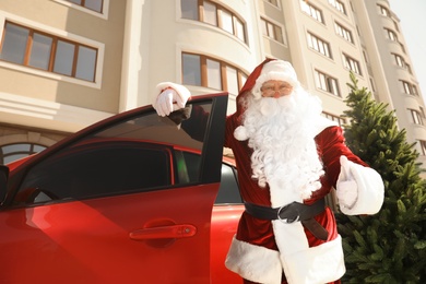 Authentic Santa Claus near car with fir tree outdoors