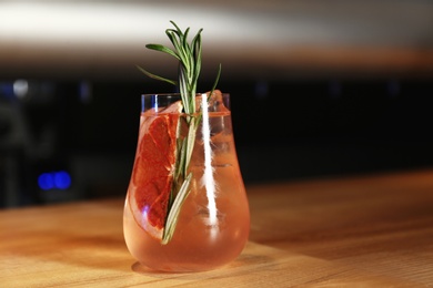 Glass of delicious cocktail with vodka on wooden counter in bar